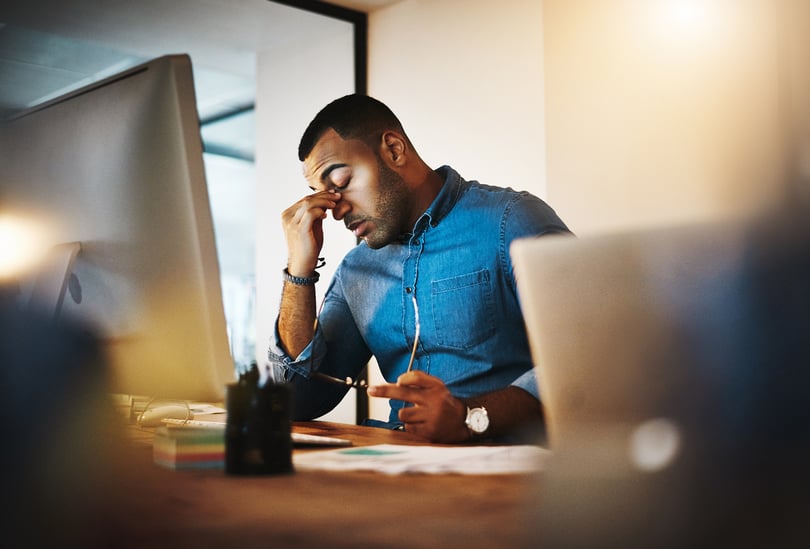 Employee sitting at a desk with his head down