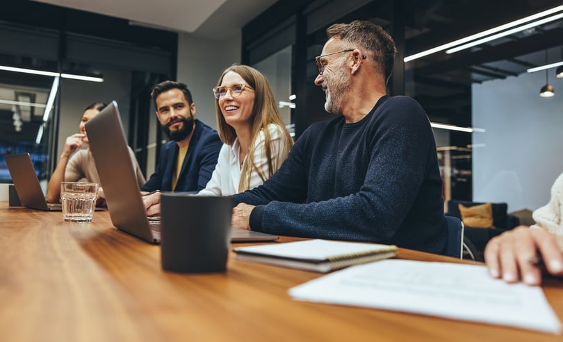 Three people at a table in front of a laptop | Benify